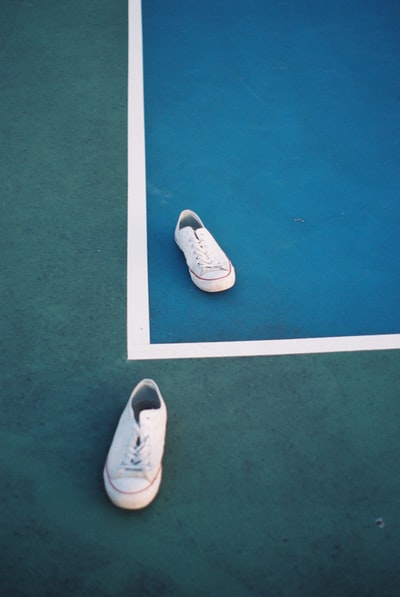 绿色地板上的白色低帮运动鞋